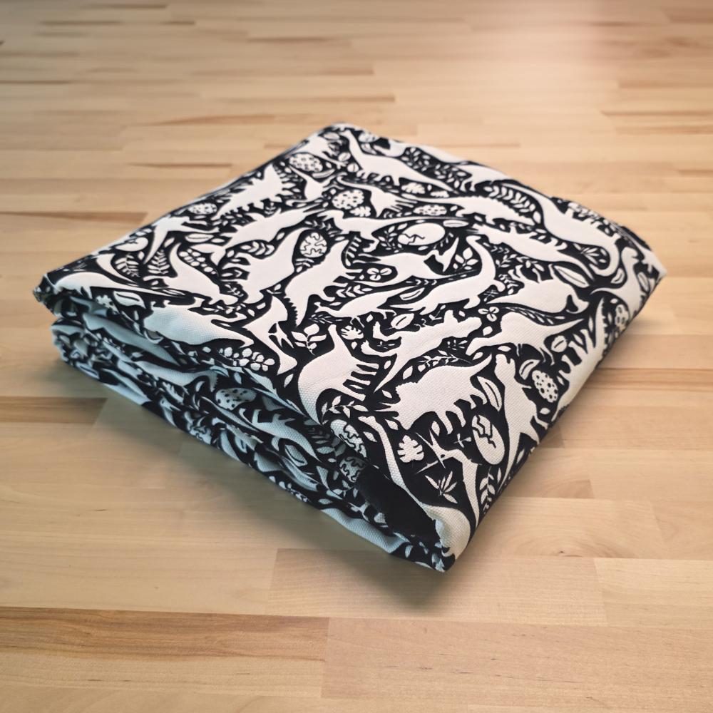 Uncolored dinosaurs with dinosaur eggs patterned blanket folded on a table