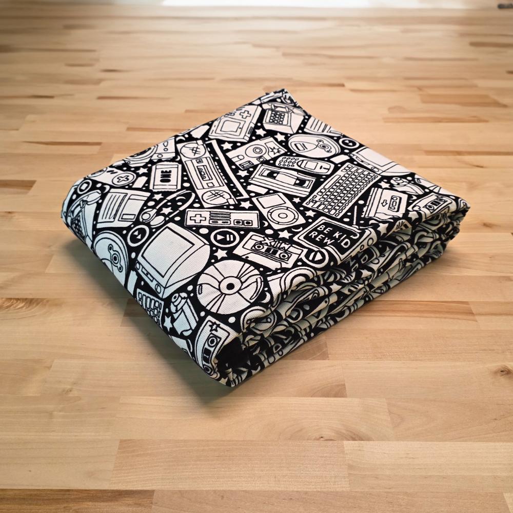 Uncolored retro technology, keyboard ,camera and stereo patterned blanket folded on a table