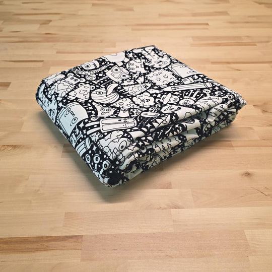 Uncolored  silly monster party patterned blanket folded on a table