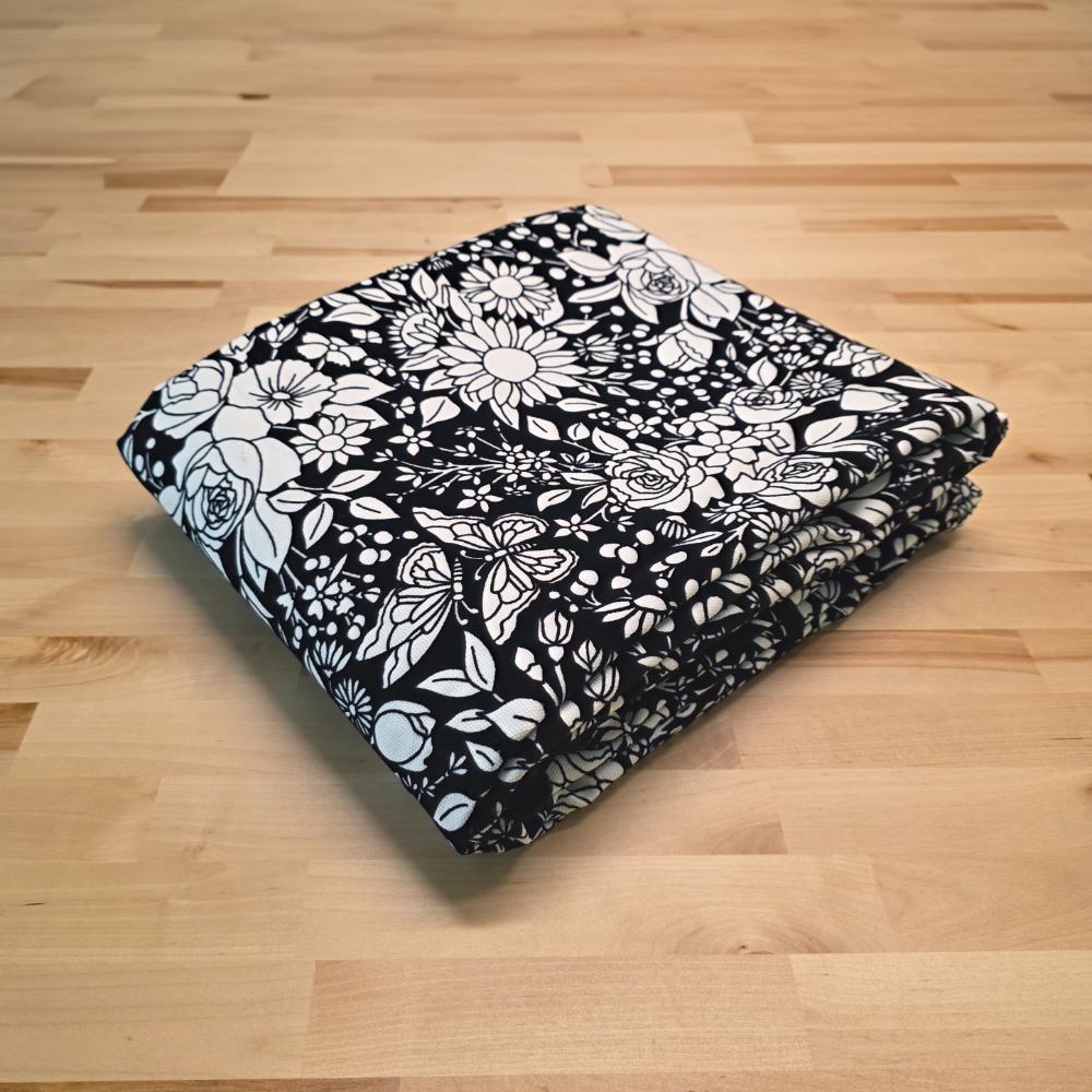 Uncolored vintage floral and butterfly patterned blanket folded on a table