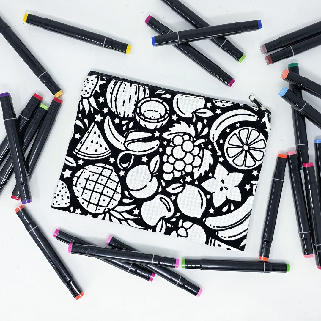Photo of a black and white flat pencil pouch with lots of colorful markers beside it indicating the customer gets to color it when they receive theirs. This is the same bag as the pencil case - Side B - this bag has images of juicy fruits on it