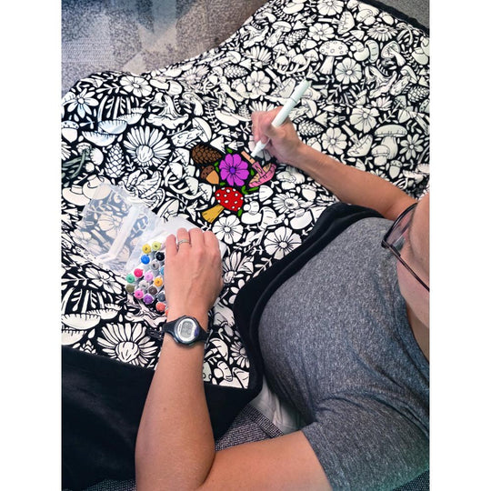 Mushroom and floral blanket with fleece lined underside being colored with bright colorful markers
