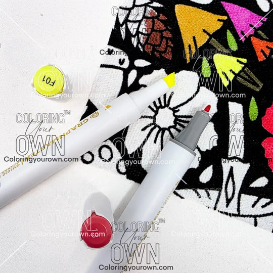 Two markers with colorful caps on a white surface with a patterned fabric background