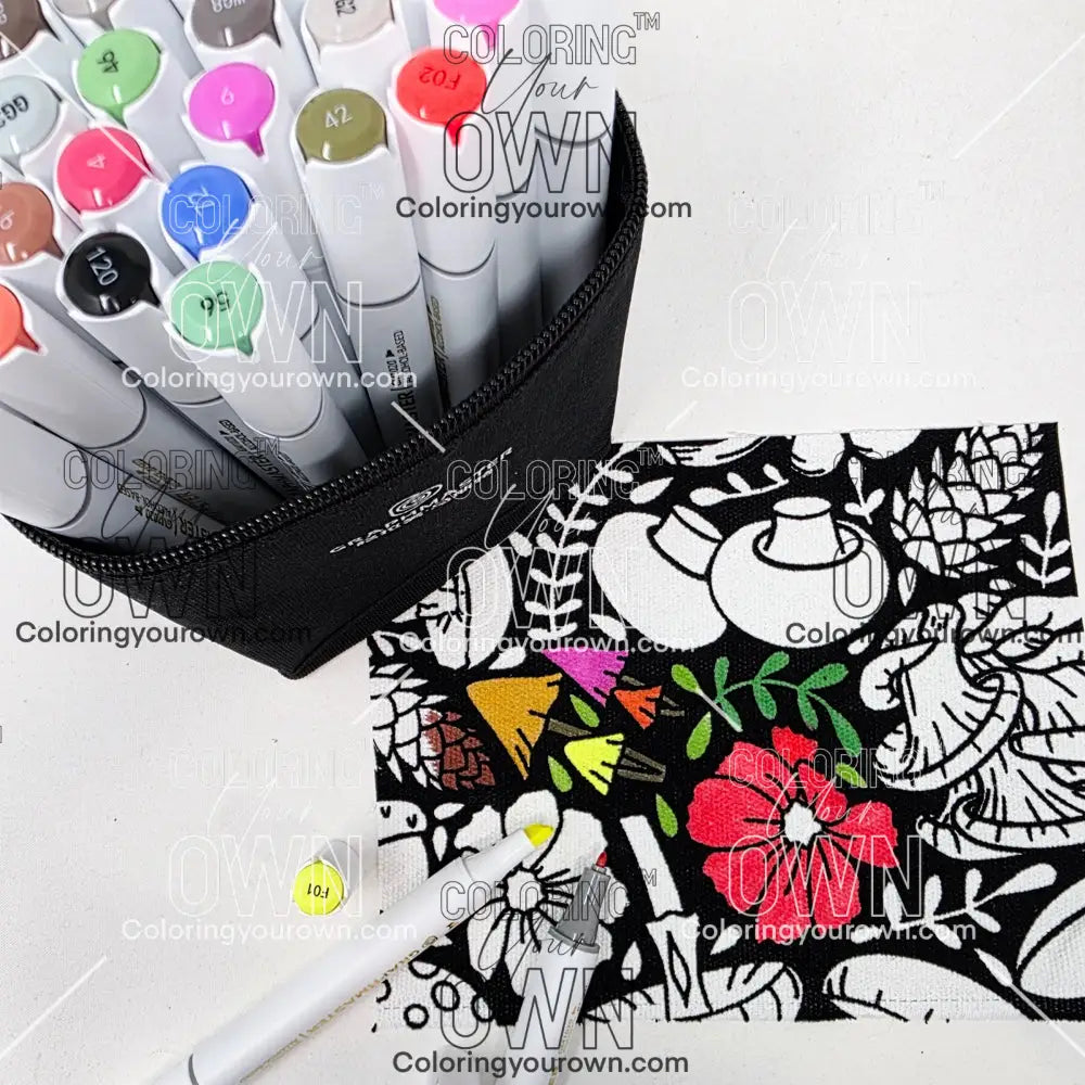 Colorful markers in a case with a coloring fabric featuring floral and mushroom designs on a white background.