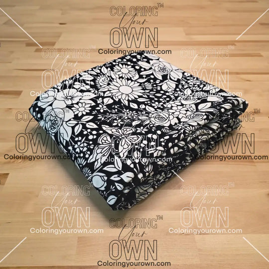Uncolored vintage floral and butterfly patterned blanket folded on a table