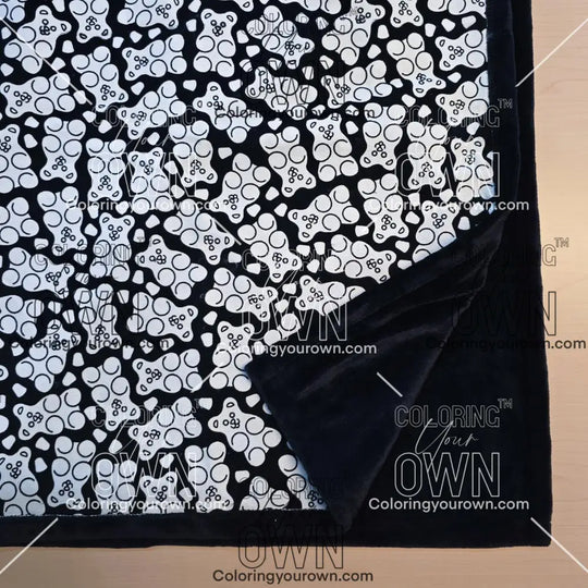 Black and white uncolored gummy bears and gumdrops patterned blanket with close up view showing black fleece lined underside