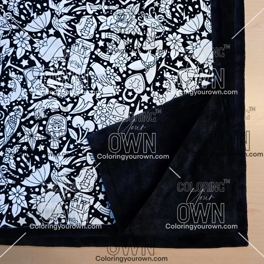 Black and white uncolored classic tattoo styles and patterns blanket with close up view showing black fleece lined underside