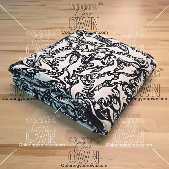 Uncolored dinosaurs with dinosaur eggs patterned blanket folded on a table