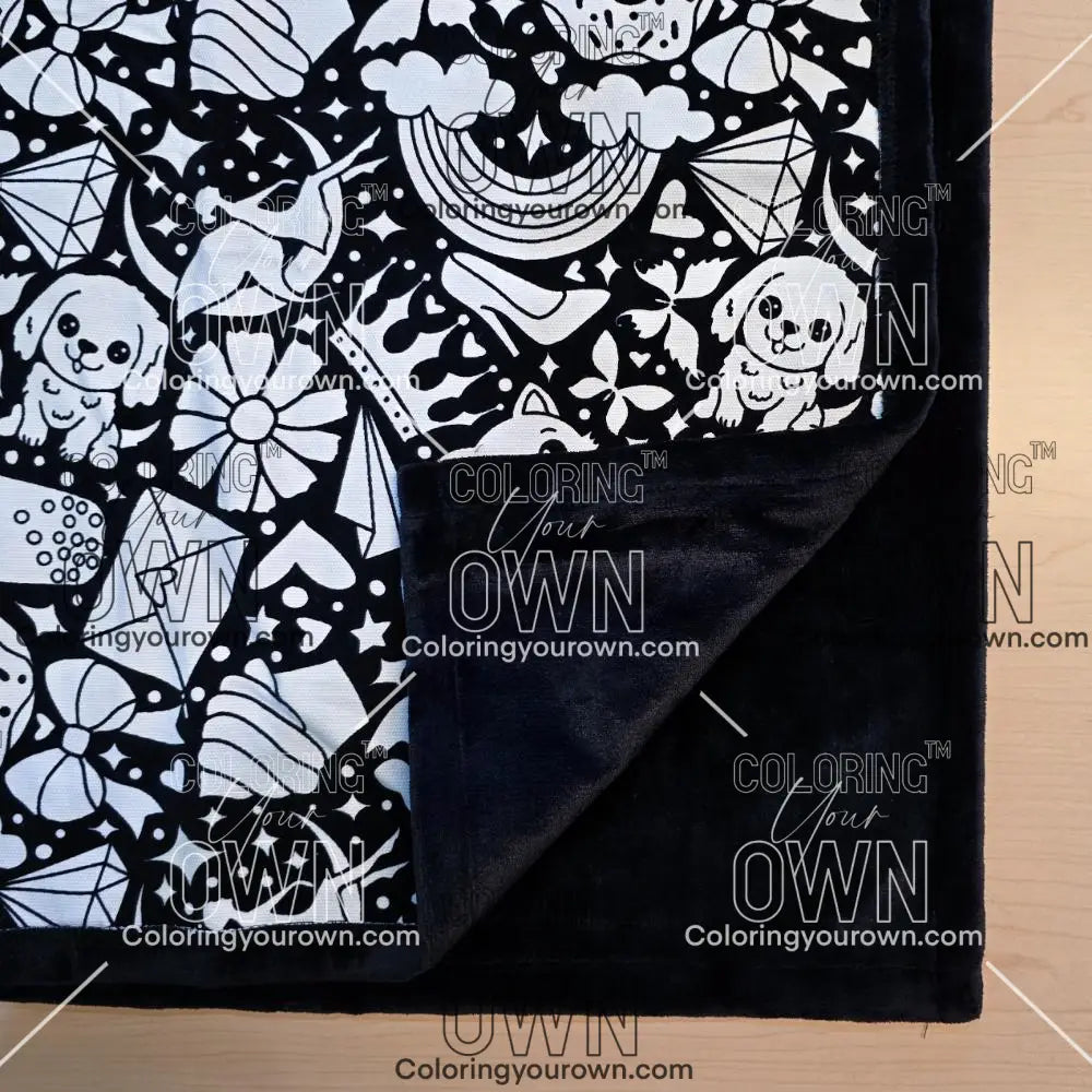 Black and white uncolored version two doodle patterned blanket with donuts, cats, cupcakes with close up view showing black fleece lined underside