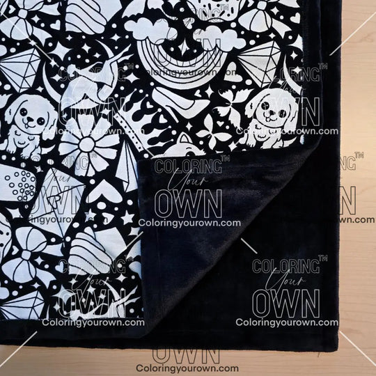 Black and white uncolored version two doodle patterned blanket with donuts, cats, cupcakes with close up view showing black fleece lined underside
