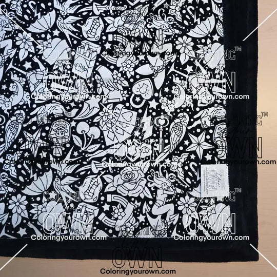 Black and white uncolored classic tattoo styles and patterns blanket with black fleece lined underside close up view