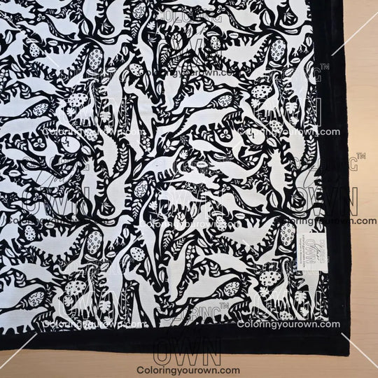 Black and white uncolored dinosaurs with dinosaur eggs patterned blanket with black fleece lined underside close up view