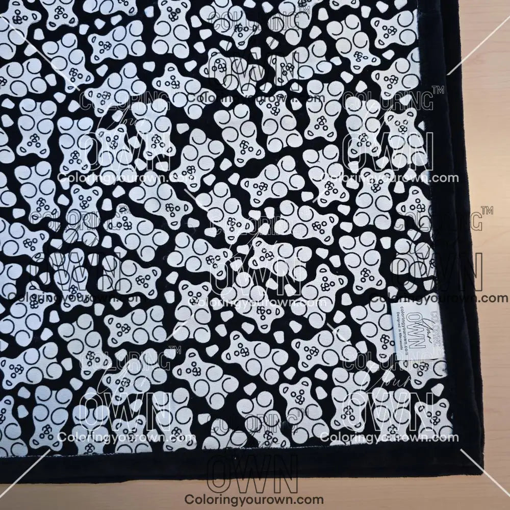 Black and white uncolored gummy bears and gumdrops patterned blanket with black fleece lined underside close up view