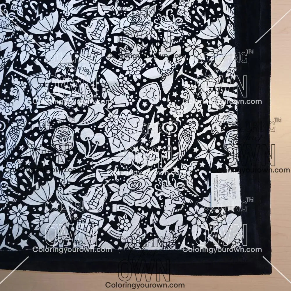 Black and white uncolored classic tattoo styles and patterns blanket with black fleece lined underside close up view
