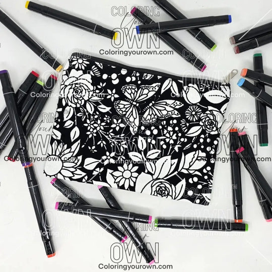 Photo of a black and white flat pencil pouch with lots of colorful markers beside it indicating the customer gets to color it when they receive theirs. This is the same bag as the pencil case - Side B - this bag has images of vintage flowers on it