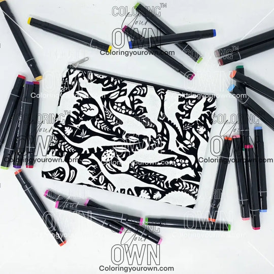 Photo of a black and white flat pencil pouch with lots of colorful markers beside it indicating the customer gets to color it when they receive theirs. This is the same bag as the pencil case and makeup bag - Side A - this bag has images of dinosaurs, foliage, and eggs