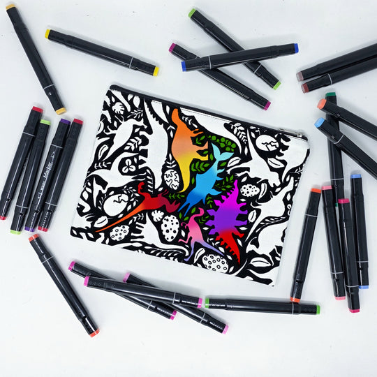 Photo of a black and white flat pencil pouch with lots of colorful markers beside it indicating the customer gets to color it when they receive theirs. This is the same bag as the pencil case and makeup bag - Side B - this bag has images of dinosaurs, foliage, and eggs