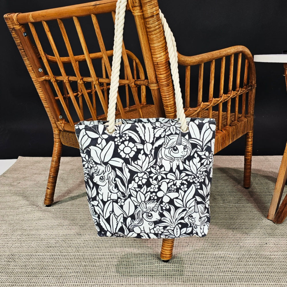 photo of a unicorn uncolored color your own tote hanging on the back of a wicker chair.