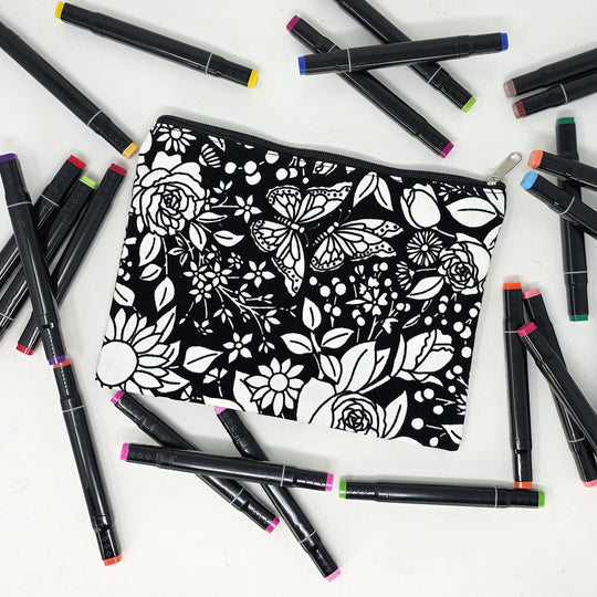 Photo of a black and white flat pencil pouch with lots of colorful markers beside it indicating the customer gets to color it when they receive theirs. This is the same bag as the pencil case - Side B - this bag has images of vintage flowers on it
